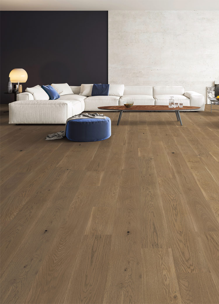 warm toned hardwood flooring in living room with large white couch and blue decor.